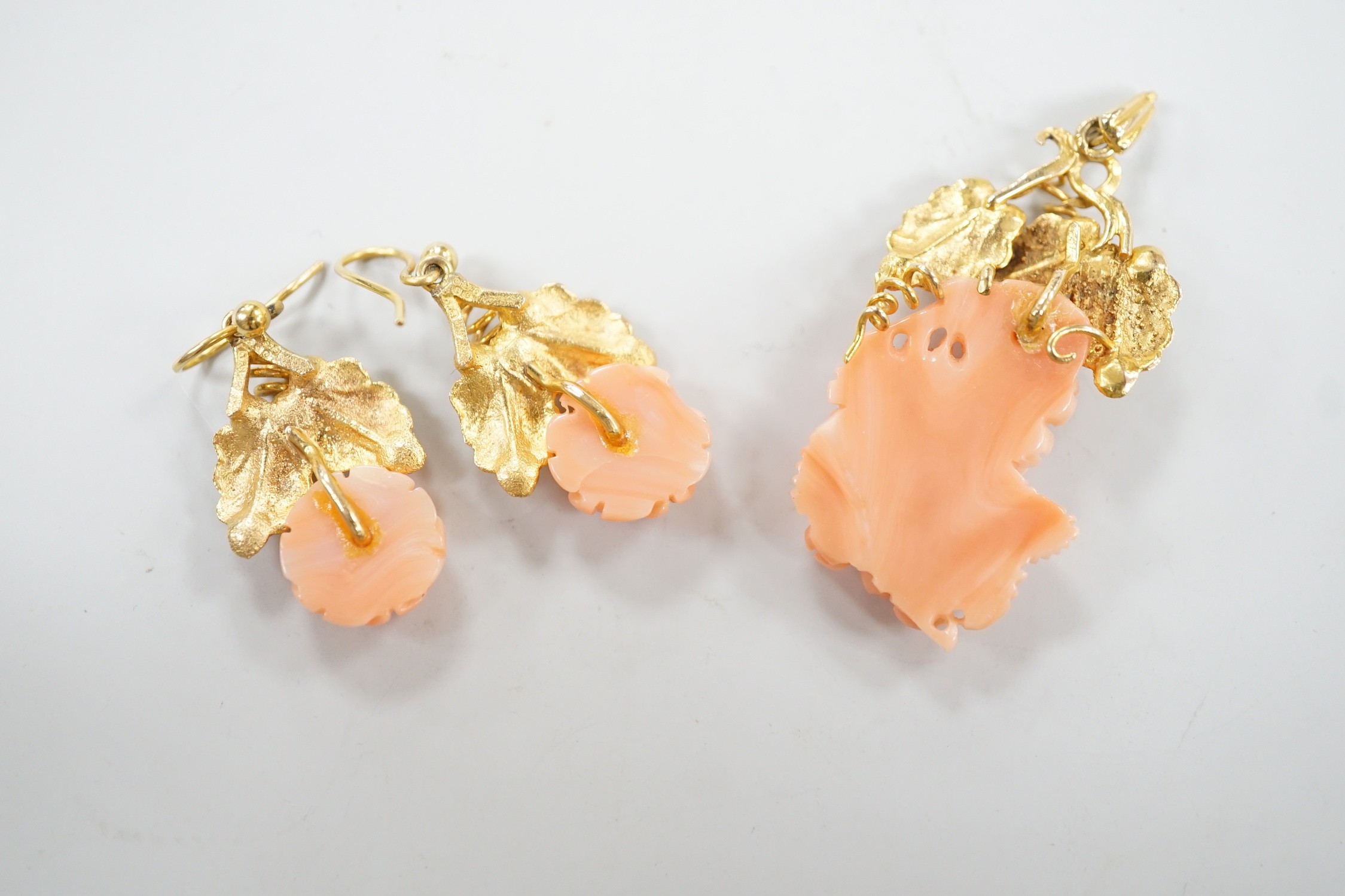 A modern suite of yellow metal and carved coral jewellery, comprising a pendant , 40mm, on chain, 45cm and a pair of matching drop earrings stamped 9ct gold, 26mm, gross 15.2 grams.